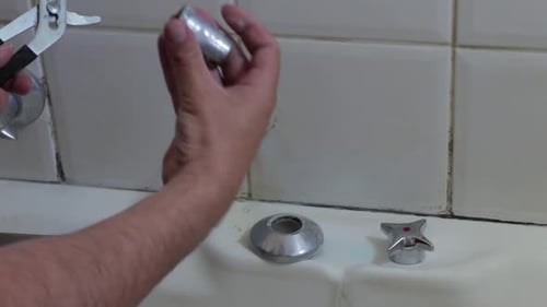 Steady shot of a man removing a pipe to repair a tap