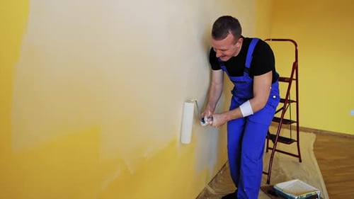 Man Painting Wall with Roller Indoors