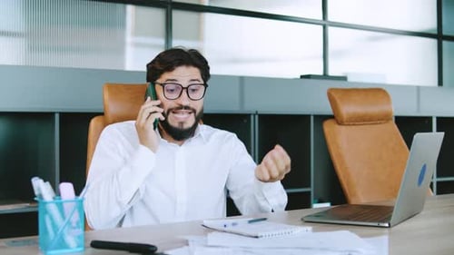 Angry Professional Man Discussing Business Over Phone While Seated in Modern Office Setting with