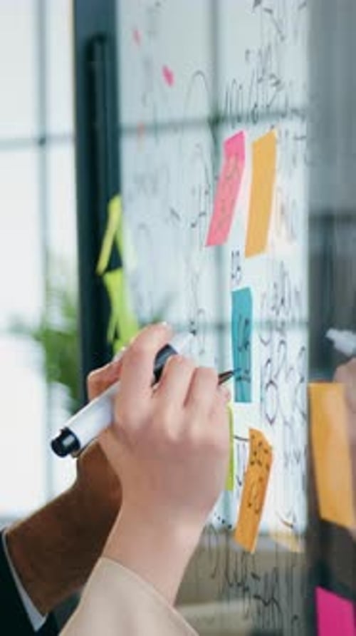 People Working Together on Sticky Notes on Glass