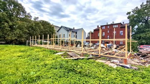 View of broken wooden house left over with structure at a neighborhood during daytime.