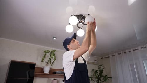 Man Adjusting Modern Ceiling Light Fixture Indoors