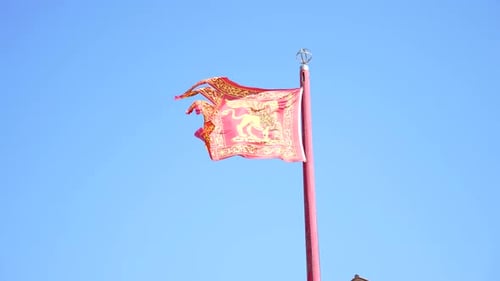 Red Flag With Gold Lion Waving Against Sky
