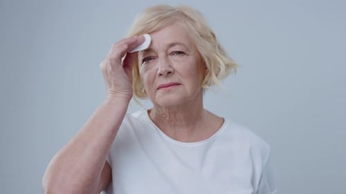 Senior Woman Gently Cleansing Face with Cotton Pad