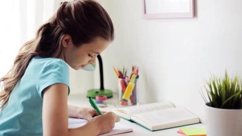 Focused girl studying and writing in notebook at desk