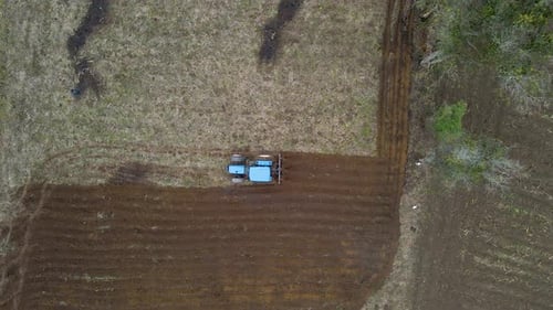 Powerful tractor plowing a field at sunrise, kicking up dust under a clear sky. Epic agricultural sc