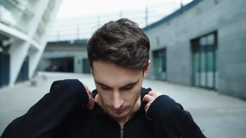 Retrato de homem bonito andando na rua em câmera lenta. Cara focado de perto corrigindo o capuz...