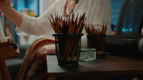 Artist Selecting Pencil from Desktop in Studio