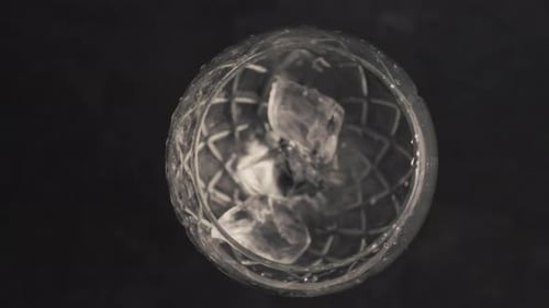 Ice cubes fall into empty faceted glass mug in super slow motion preparation