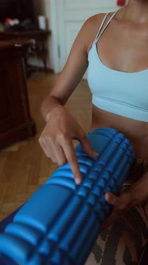 Woman Demonstrates Using Foam Roller in Apartment