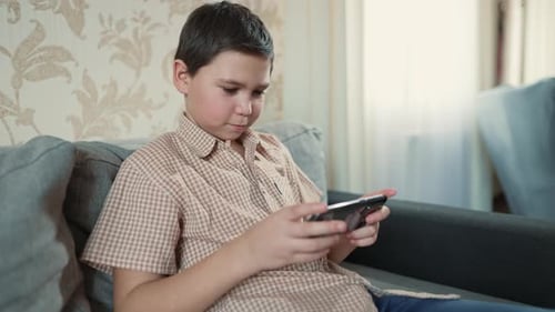 Boy Using a Phone on a Couch at Home