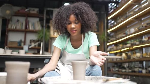 Young women is making earthenware at workshop.
