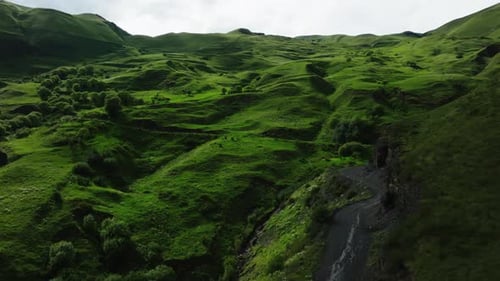 Winding Road Through Rolling Hills of Lush Green Pasture in Expansive Rural Landscape