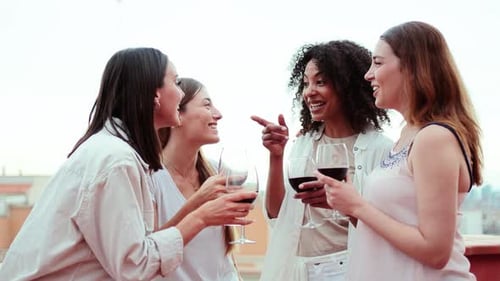 Four women laugh and toast with wine glasses