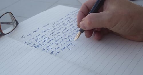 Male Hand Writing Down Memoir On A Journal With A Fountain Pen. close up