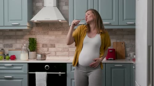 Pregnant Woman Dancing and Singing in Kitchen