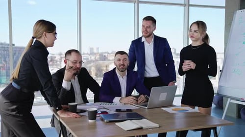 Collaborating team of men and women in the office. Friendly people co working and discussing ideas.