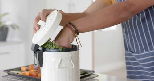 Biracial man with fresh vegetables on table throwing waste out in kitchen, slow motion