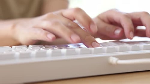 Frau tippt auf weißer Tastatur am Holztisch, Nahaufnahme