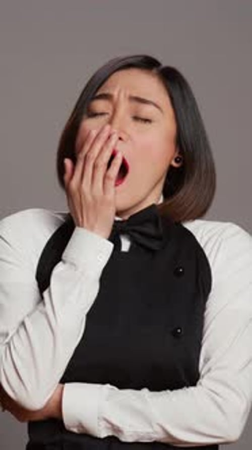 Vertical Video Exhausted Waitress with Apron Yawning Over Grey Background