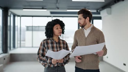 Business Colleagues Discuss Blueprints in a Modern Office Space