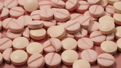 Round Pills Scattered on Pink Surface