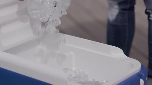 Se vierte una bolsa de hielo en una hielera azul.