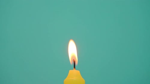 Yellow Candle Lit on Blue Background
