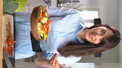 Woman Holds Bowl with Fresh Vegetables in Kitchen