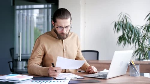 Man working with laptop and documents in office