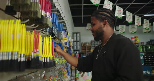 Man arranging tools and brushes on racks in a paint store, holding a ...