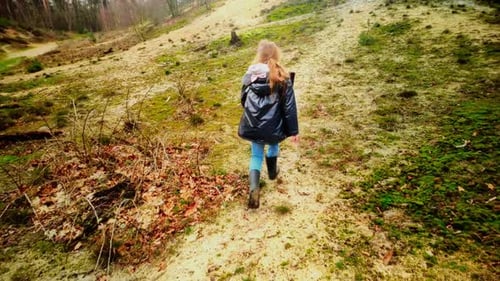 Girl walks through dunes in Dutch national park Maasduinen rear view slowmotion