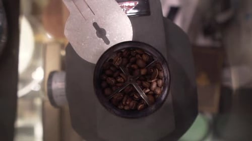 Geröstete Kaffeebohnen mahlen für Espresso. Nahaufnahme der Schleifmaschine von oben