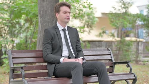 Man in Suit Sits on Bench, Rubs Temples
