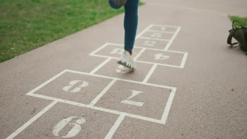 Close-up of young woman hopscotching on city playground