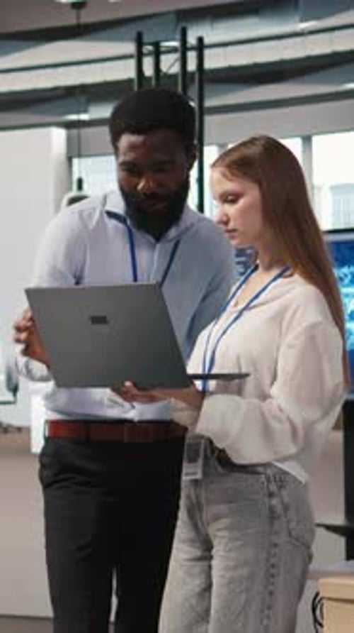 Vertical Video Junior Dev and Colleague in Office Reviewing AI System Metrics
