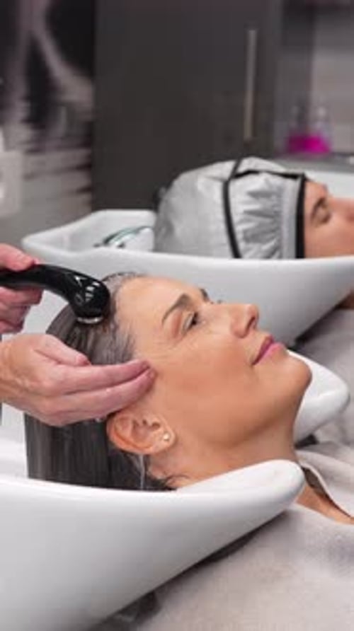 Friseur wäscht die Haare des Kunden in einer Salonspüle