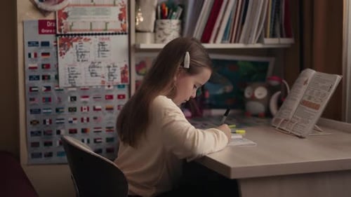 Girl Writes in Notebook at Home Desk