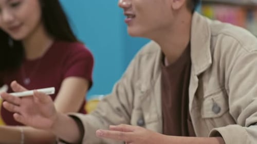 Groupmates Discussing Ideas for School Project while Sitting at Library Table