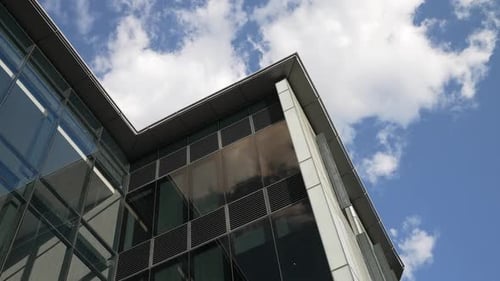 Modern office building with big glass windows and view of the blue sky and clouds above on a clear d