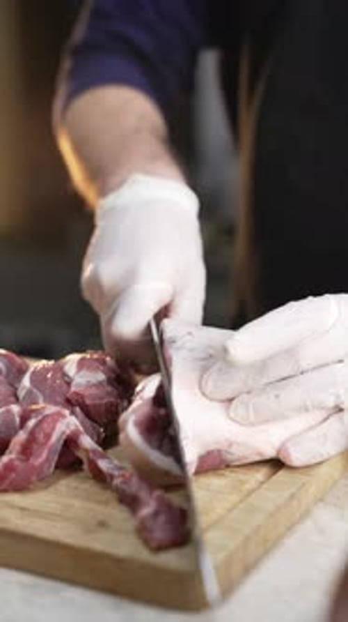 Hands Slicing Meat with a Knife