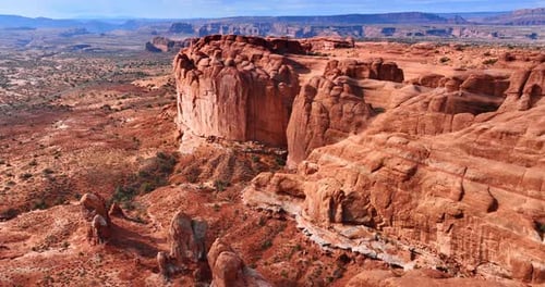 Flying closer to the huge red rocks with steep walls in the dry desert.