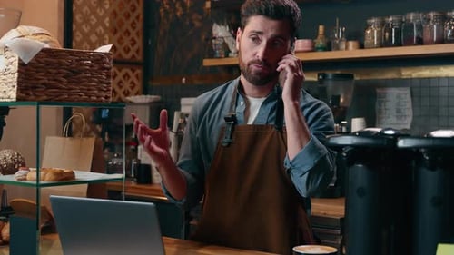 Man Working in Cafe Talking on Phone