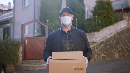 Delivery Man Courier with Face Mask Delivering Parcel Boxes in Town