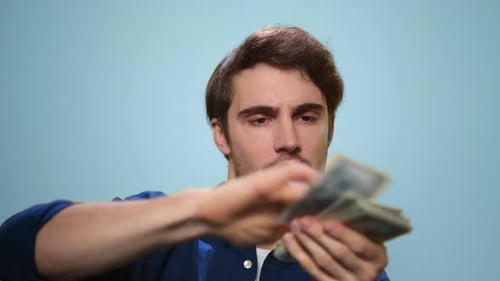 Close Up Happy Man Throwing Money Cash In Slow Motion. Rich Guy Holding Money Cash On Blue Backgr...