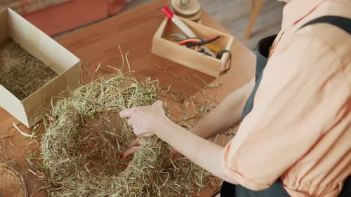 Woman Crafts Rustic Wreath with Twine at Wooden Table