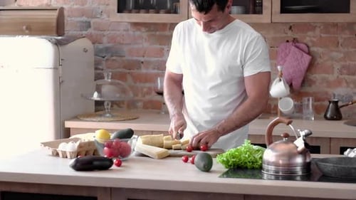 Man Chopping Cheese and Tomatoes in Kitchen