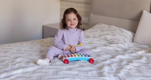 Girl Playing Xylophone on Bed at Home
