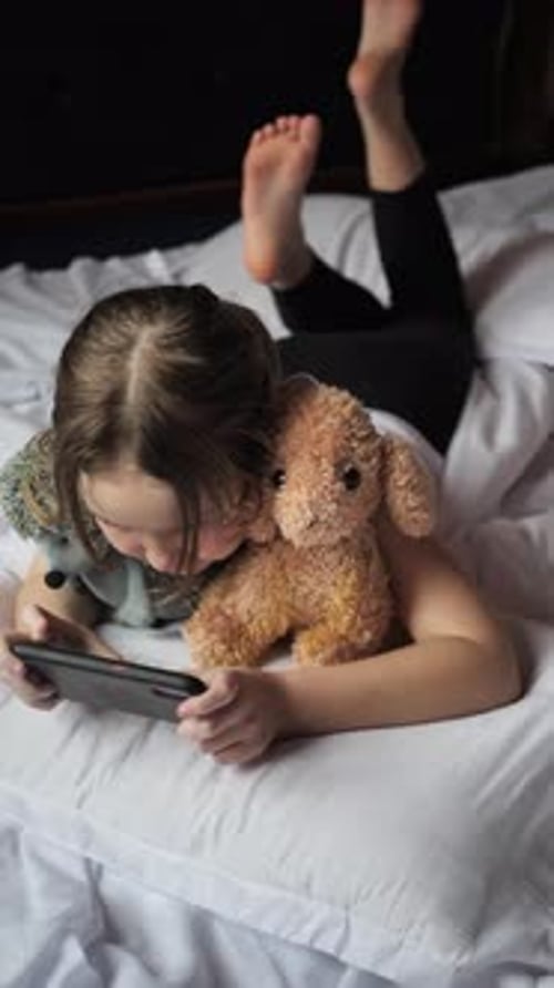 Girl Lying on Bed With Phone and Teddy Bear
