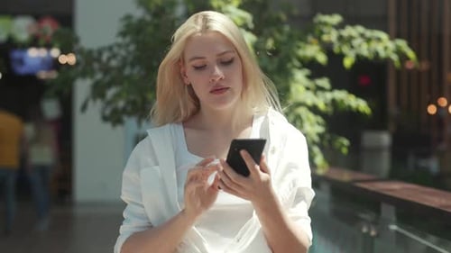 Blonde Woman Using Smartphone in Urban Setting